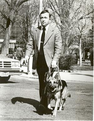 Robert Whitstock and dog guide crossing a city street. Photo courtesy of the Archives of the American Foundation for the Blind