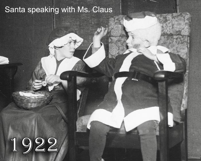 1922: Young elementary student dresses as Santa Claus speaking to Ms. Claus 