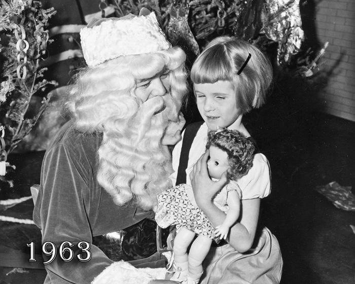 1963: Young girl getting a doll from Santa Claus