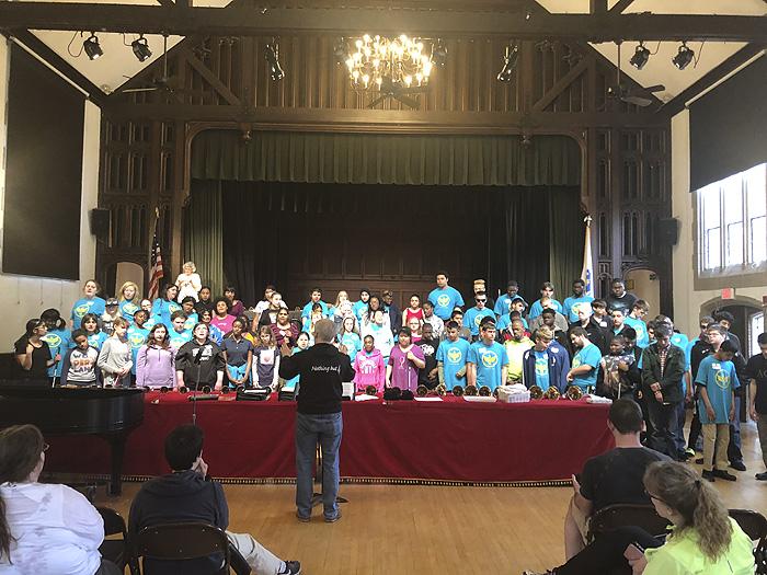 Wide angle image of the united chorus from 7 schools singing in rehersal