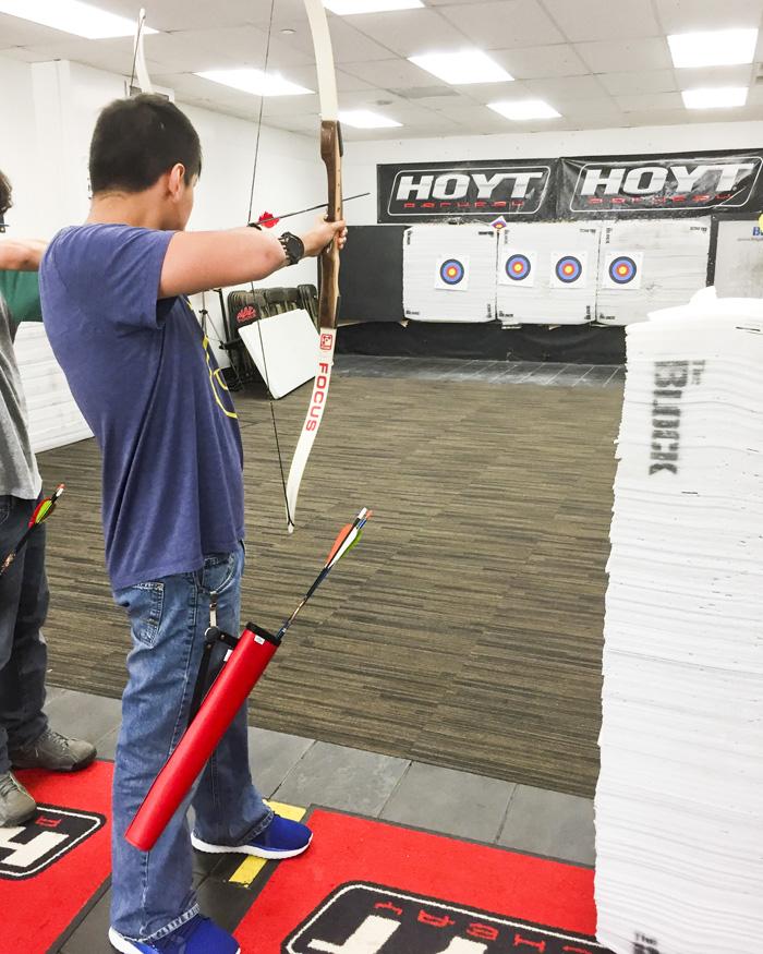 Students with bow shooting an arrow at a distant target.