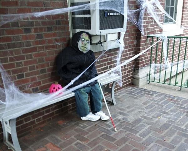 On the front porch bench sits a creepy ghoul waiting to scare someone. 
